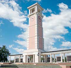 A white clock tower with a balcony in front.