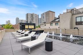 the rooftop pool of a building with white lounge chairs and a fountain