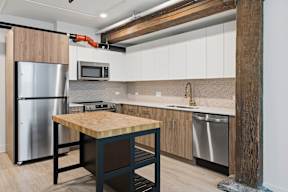 A kitchen with a wooden table and stainless steel appliances.