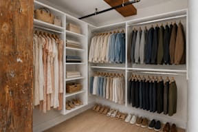 A walk in closet with clothes and shoes.