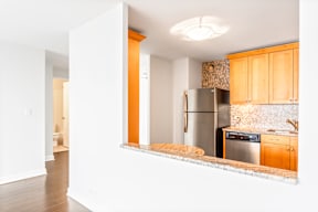 A kitchen with wooden cabinets and a stainless steel refrigerator.