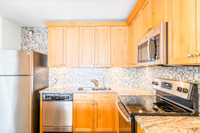 A kitchen with wooden cabinets and a stainless steel refrigerator.