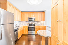A kitchen with wooden cabinets and a stainless steel refrigerator.