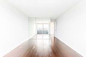 A long, empty room with wooden floors and white walls.