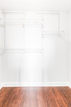 Empty white shelves on a wall above a wooden floor.