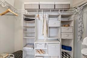 a walk in closet with white shelves and drawers