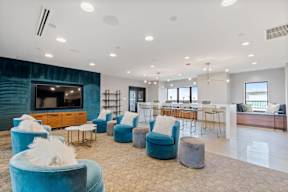 a living room with blue chairs and a bar and a television