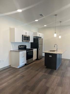 A kitchen with a black fridge and white cabinets.