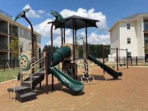 A playground with a green slide and a black metal structure.
