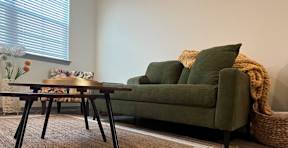 A green couch with a brown table in front of it.