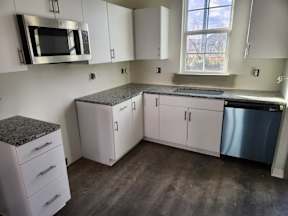 A kitchen with white cabinets and a granite countertop.