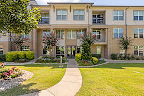 A building with a green lawn in front at The Preserve at Preston Trails Apartments, Cedar Hill, TX