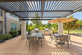 A patio with a table and chairs under a metal roof at The Preserve at Preston Trails Apartments, Cedar Hill, TX