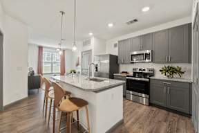 A modern kitchen with wooden chairs and stainless steel appliances at The Preserve at Preston Trails Apartments, Cedar Hill