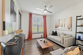 A living room with a couch, a coffee table, and a painting on the wall at The Preserve at Preston Trails Apartments, Cedar Hill