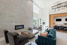 A modern living room with a fireplace and a green couch at The Preserve at Preston Trails Apartments, Cedar Hill, Texas