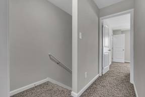 A hallway with a carpeted floor and white walls.at Arrowood Farms, Clarksville Tennessee