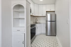 A kitchen with white cabinets and a silver refrigerator.