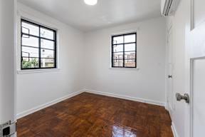 A room with wooden floors and two windows.