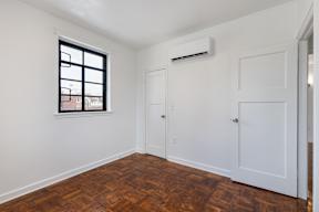 A room with a window and a wood floor.