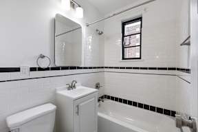 A white bathroom with black and white tiles.