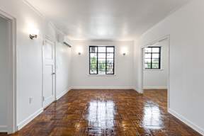 A room with wooden floors and two windows.
