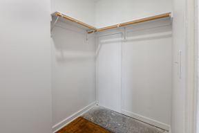 A white closet with a wooden shelf above it.