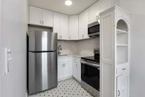 A kitchen with a stainless steel refrigerator and white cabinets.