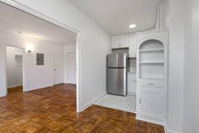 A kitchen with a refrigerator, oven, and wooden floors.