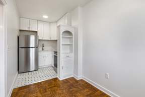 A kitchen with white cabinets and a silver refrigerator.