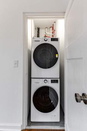 A white washing machine is in a small space between a door and a wall.