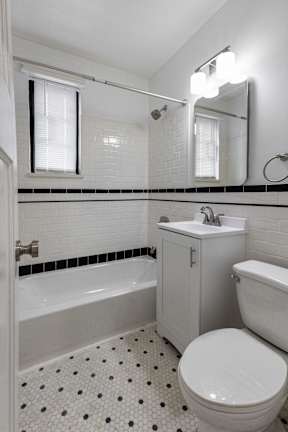 A white toilet with a black and white tiled floor in a bathroom.