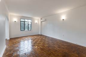 A room with a window and a wooden floor.