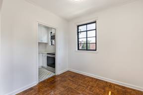 A kitchen with white walls and a wooden floor.