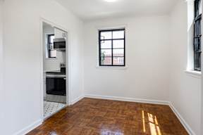 A kitchen area with a window and a wooden floor.