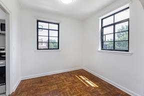A room with two windows and wooden flooring.
