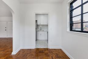 A kitchen with white cabinets and a wooden floor.