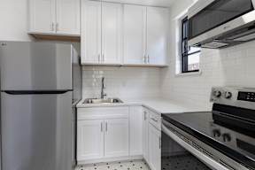 A kitchen with white cabinets and a black stove top oven.