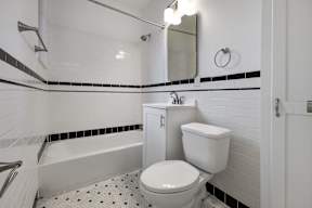 A white toilet sits in a bathroom with black and white tiles.