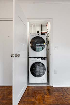 A white door opens to a laundry room with a washer and dryer.