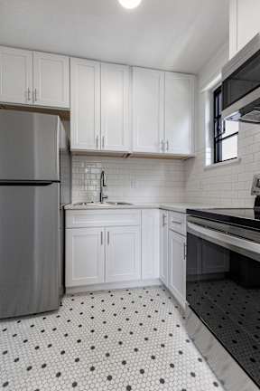A kitchen with white cabinets and a black and white floor.