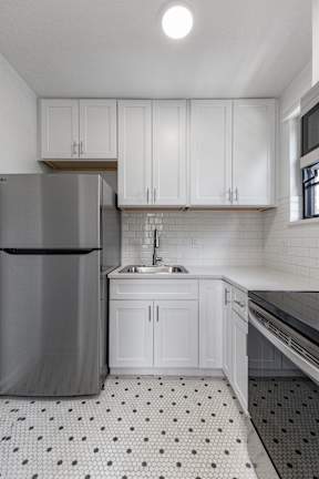 A kitchen with a refrigerator, sink, and cabinets.
