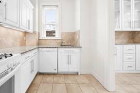 A kitchen with white cabinets and a tiled backsplash.