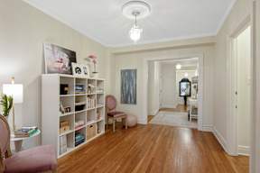 A room with a wooden floor and a white wall with a painting hanging on it.