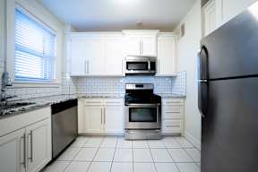 A kitchen with white cabinets and a black refrigerator.