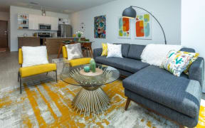 a living room with a gray couch and yellow chairs