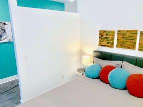 a seating area with a couch and pillows and a wall with paintings