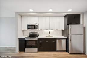 Harbourline Apartments, St Paul a kitchen with white cabinets and black appliances and a stainless steel refrigerator