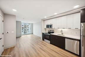Harbourline Apartments, St Paul a kitchen and living room with white cabinets and a stainless steel refrigerator