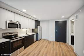 Harbourline Apartments, St Paul a kitchen with white cabinets and black appliances and a black door
